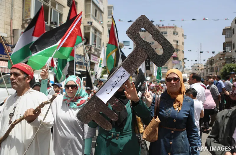 Palestinians hold a flag during in a procession on the 68th anniversary of the "Nakba" in the West Bank city of Ramallah on May 15, 2016. "Nakba" means in Arabic "catastrophe" in reference to the birth of the state of Is...