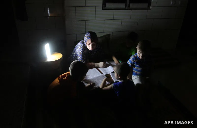 Palestinian boys study on lanterns light during a power outage in Rafah in the southern Gaza Strip on May 18, 2016. Photo by Abed Rahim Khatib