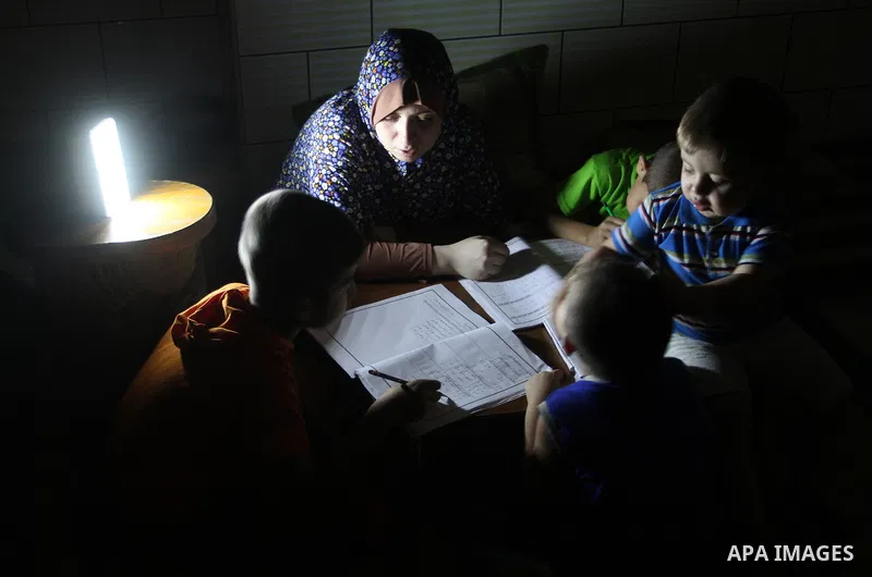 Palestinian boys study on lanterns light during a power outage in Rafah in the southern Gaza Strip on May 18, 2016. Photo by Abed Rahim Khatib
