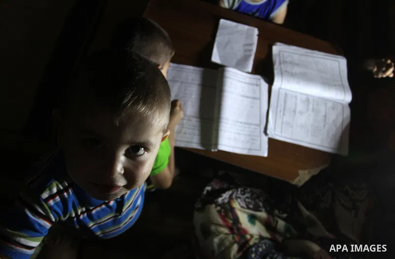 Palestinian boys study on lanterns light during a power outage in Rafah in the southern Gaza Strip on May 18, 2016. Photo by Abed Rahim Khatib