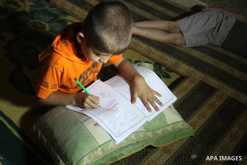 Palestinian boys study on lanterns light during a power outage in Rafah in the southern Gaza Strip on May 18, 2016. Photo by Abed Rahim Khatib