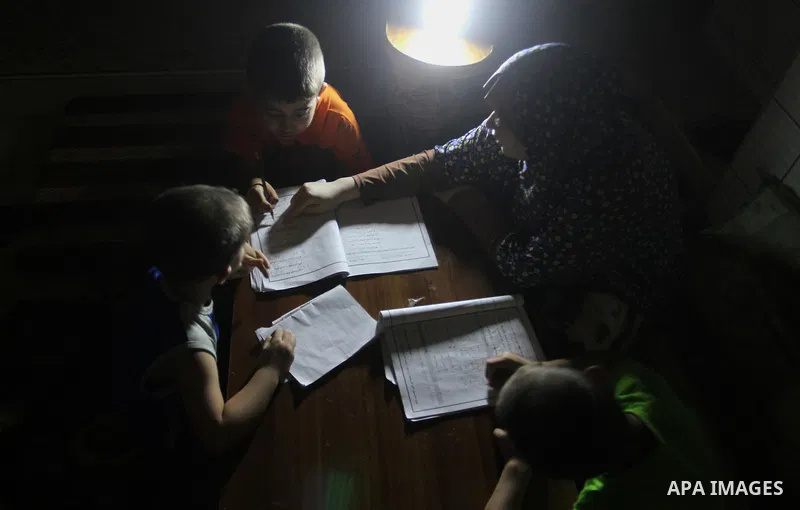 Palestinian boys study on lanterns light during a power outage in Rafah in the southern Gaza Strip on May 18, 2016. Photo by Abed Rahim Khatib