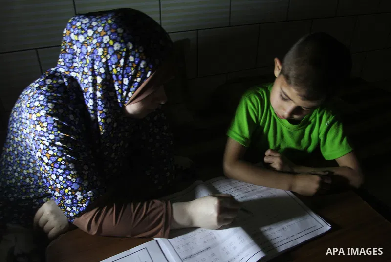 Palestinian boys study on lanterns light during a power outage in Rafah in the southern Gaza Strip on May 18, 2016. Photo by Abed Rahim Khatib