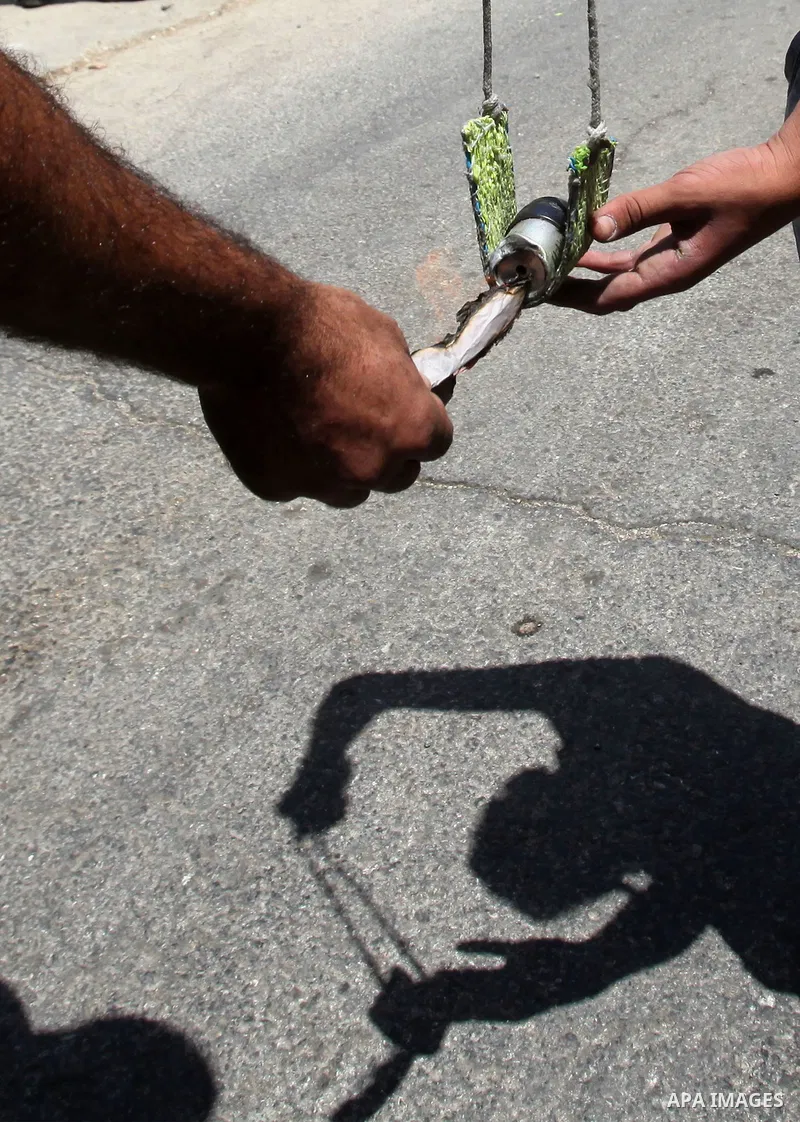 Palestinian protesters use a slingshot to throw a molotov cocktail towards Israeli security forces during clashes following a demonstration against the expropriation of Palestinian land by Israel, on May 20, 2016 in the...