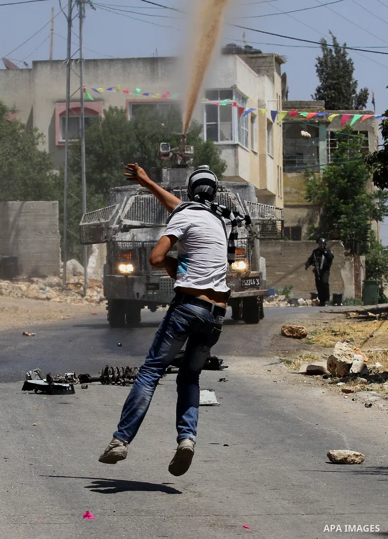 A Palestinian protester uses a slingshot to throw stones towards Israeli security forces during clashes following a demonstration against the expropriation of Palestinian land by Israel, on May 20, 2016 in the village of...