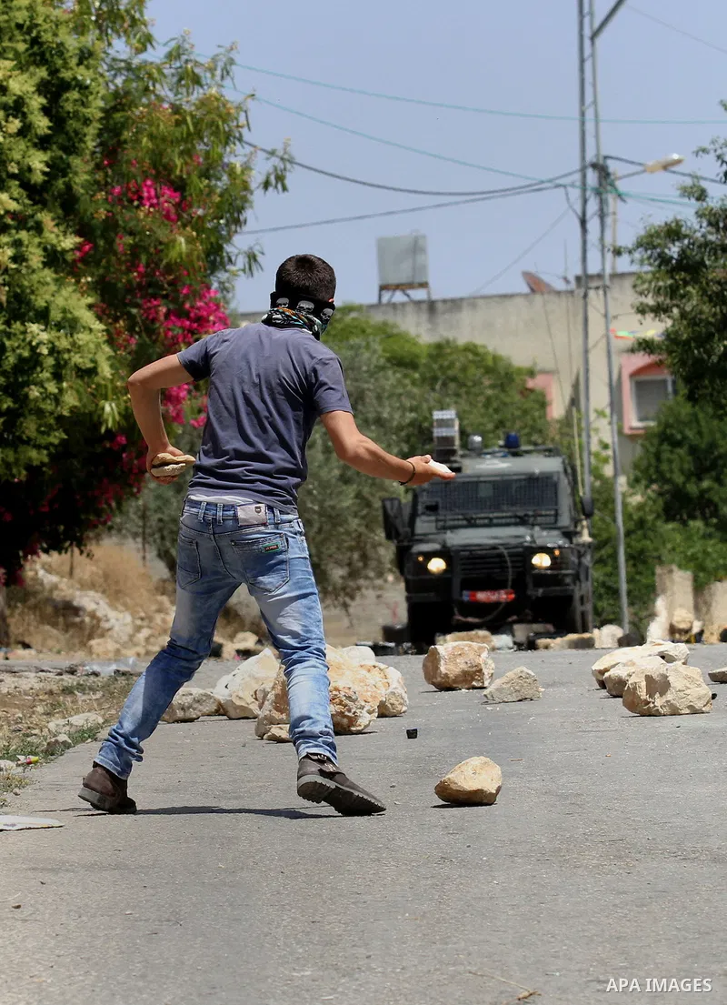 A Palestinian protester uses a slingshot to throw stones towards Israeli security forces during clashes following a demonstration against the expropriation of Palestinian land by Israel, on May 20, 2016 in the village of...