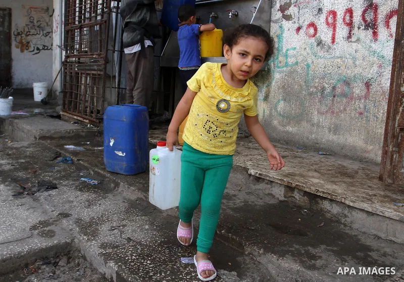 Palestinian children fill plastic bottles and jerry cans with drinking water from a public tap in Rafah in the southern Gaza strip, on May 22, 2016. Photo by Abed Rahim Khatib