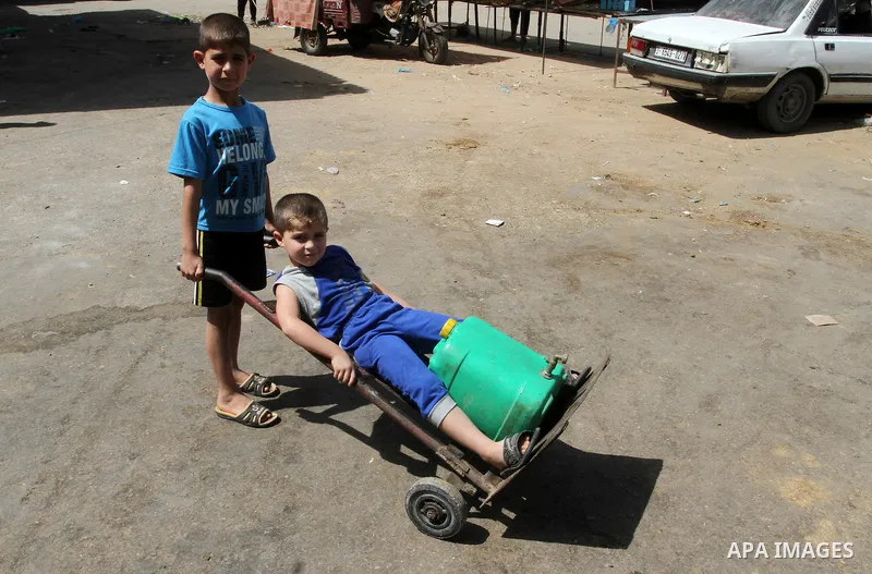 A Palestinian child rides a cart carrying cans filled with drinking water from a public tap in Rafah in the southern Gaza strip, on May 22, 2016. Photo by Abed Rahim Khatib