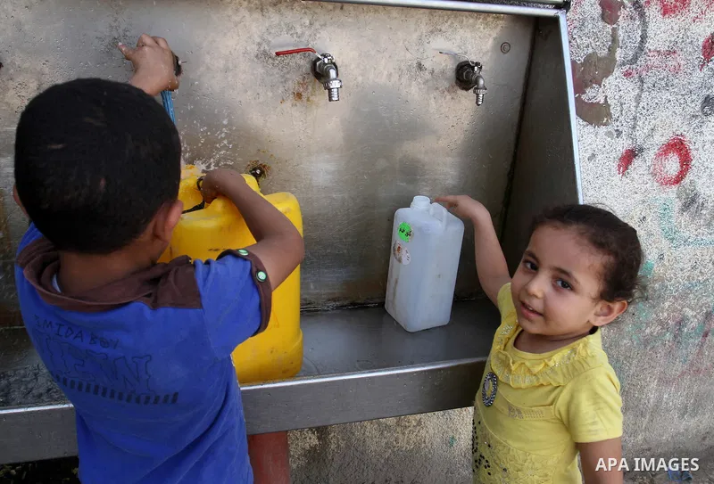 Palestinian children fill plastic bottles and jerry cans with drinking water from a public tap in Rafah in the southern Gaza strip, on May 22, 2016. Photo by Abed Rahim Khatib