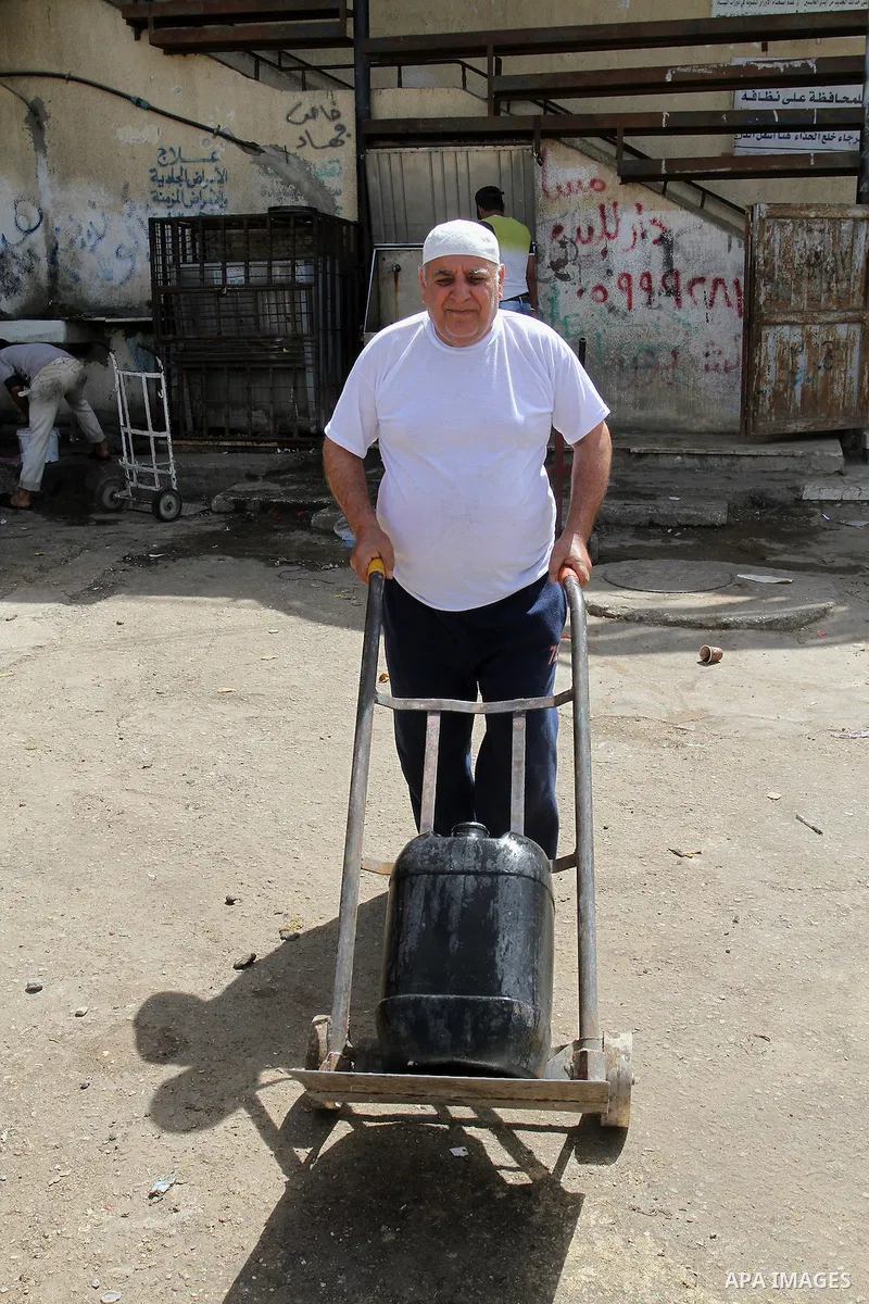 A Palestinian man rides a cart carrying cans filled with drinking water from a public tap in Rafah in the southern Gaza strip, on May 22, 2016. Photo by Abed Rahim Khatib