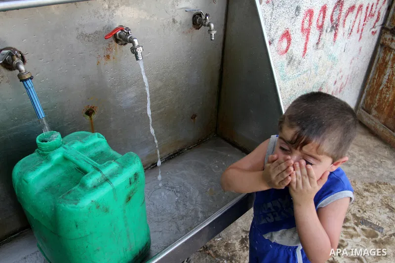 Palestinian children fill plastic bottles and jerry cans with drinking water from a public tap in Rafah in the southern Gaza strip, on May 22, 2016. Photo by Abed Rahim Khatib