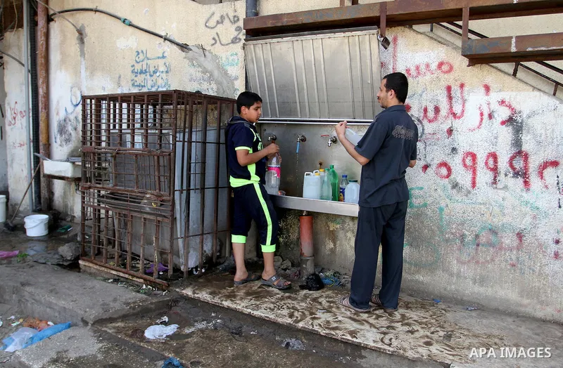 Palestinians fill plastic bottles and jerry cans with drinking water from a public tap in Rafah in the southern Gaza strip, on May 22, 2016. Photo by Abed Rahim Khatib