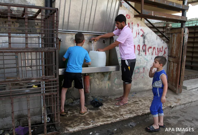 Palestinian children fill plastic bottles and jerry cans with drinking water from a public tap in Rafah in the southern Gaza strip, on May 22, 2016. Photo by Abed Rahim Khatib