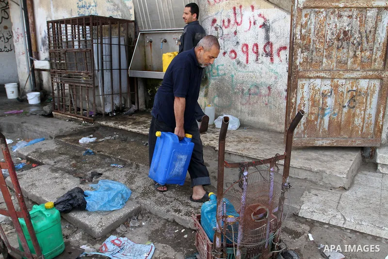 A Palestinian man fills plastic bottles and jerry cans with drinking water from a public tap in Rafah in the southern Gaza strip, on May 22, 2016. Photo by Abed Rahim Khatib