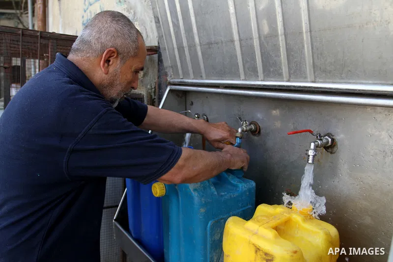 A Palestinian man fills plastic bottles and jerry cans with drinking water from a public tap in Rafah in the southern Gaza strip, on May 22, 2016. Photo by Abed Rahim Khatib