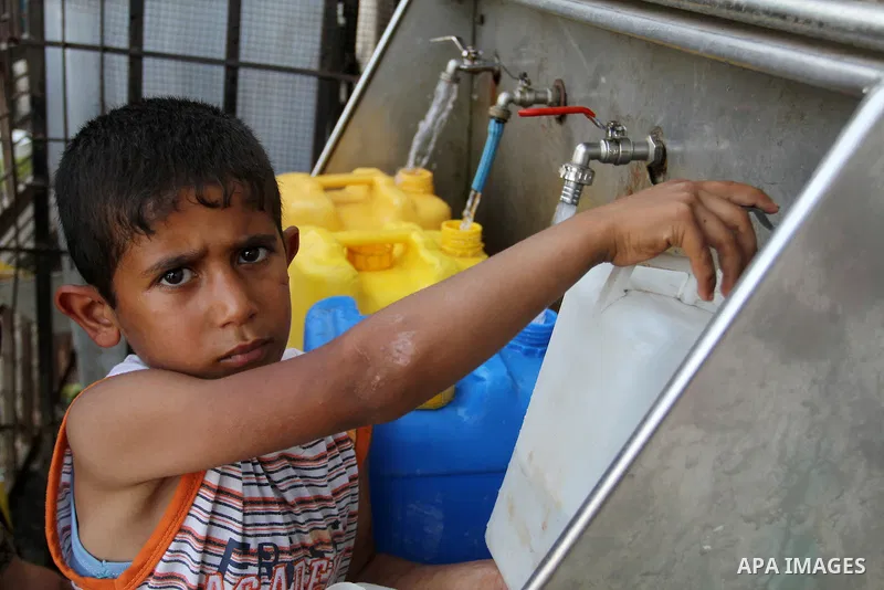 A Palestinian boy fills plastic bottles and jerry cans with drinking water from a public tap in Rafah in the southern Gaza strip, on May 22, 2016. Photo by Abed Rahim Khatib