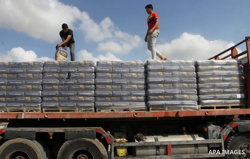 Palestinian workers stand on a truck loaded with bags of cement after it entered the southern Gaza Strip from Israel through the Kerem Shalom crossing in Rafah on May 23, 2016. Israel said on May 22 it was lifting a ban...