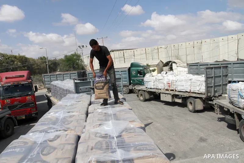 A Palestinian worker stands on a truck loaded with bags of cement after it entered the southern Gaza Strip from Israel through the Kerem Shalom crossing in Rafah on May 23, 2016. Israel said on May 22 it was lifting a ba...