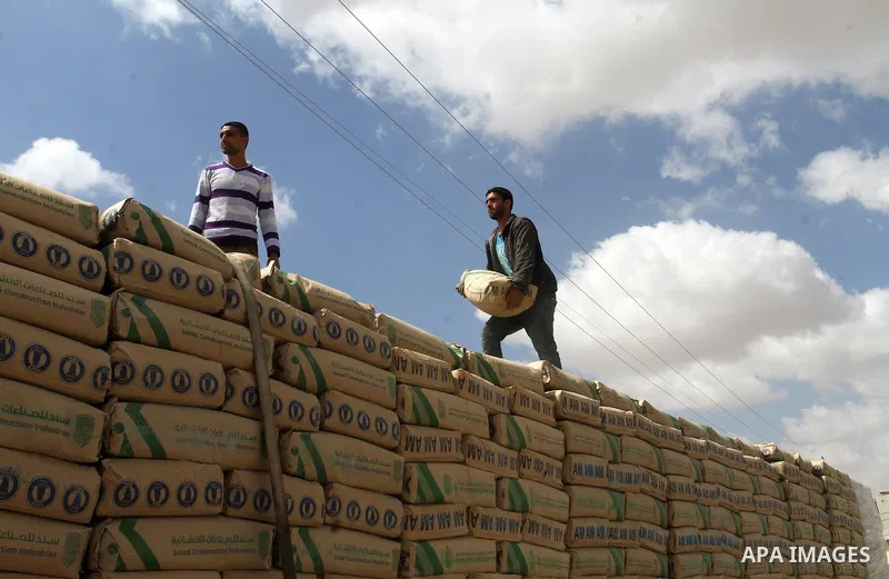 Palestinian workers stand on a truck loaded with bags of cement after it entered the southern Gaza Strip from Israel through the Kerem Shalom crossing in Rafah on May 23, 2016. Israel said on May 22 it was lifting a ban...