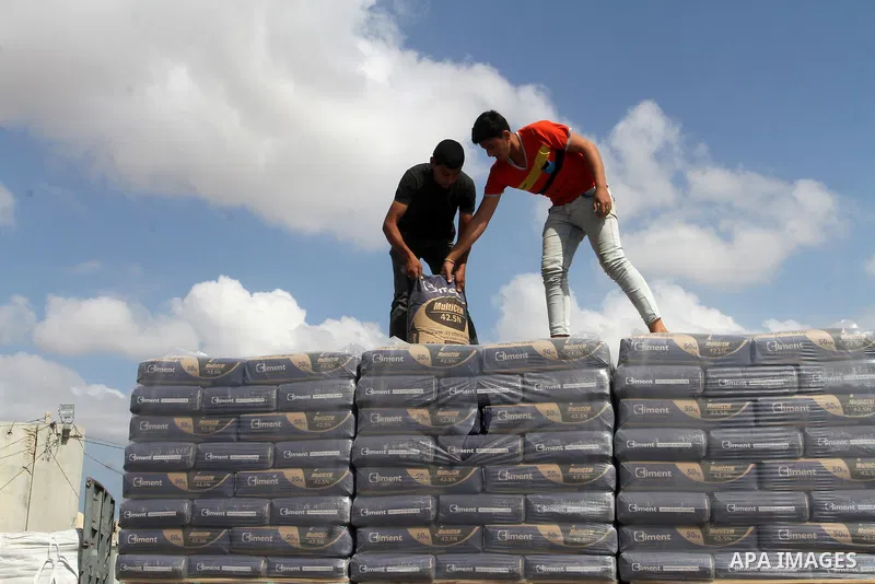 Palestinian workers stand on a truck loaded with bags of cement after it entered the southern Gaza Strip from Israel through the Kerem Shalom crossing in Rafah on May 23, 2016. Israel said on May 22 it was lifting a ban...