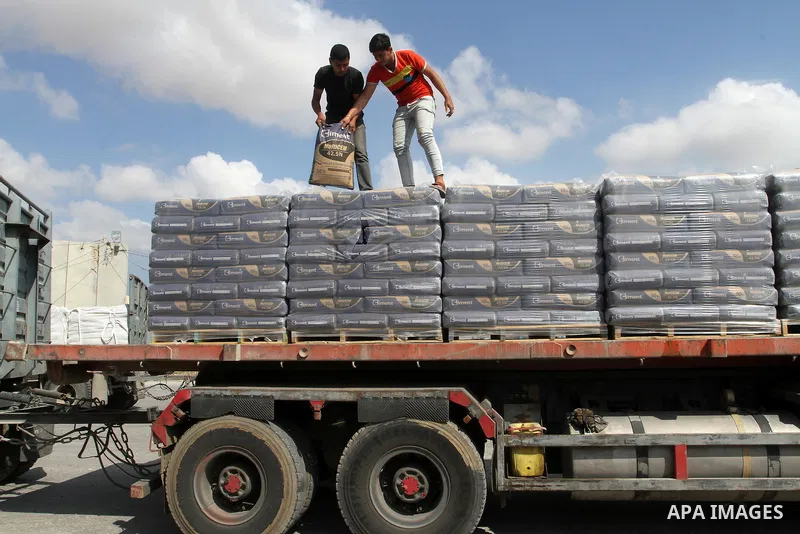 Palestinian workers stand on a truck loaded with bags of cement after it entered the southern Gaza Strip from Israel through the Kerem Shalom crossing in Rafah on May 23, 2016. Israel said on May 22 it was lifting a ban...
