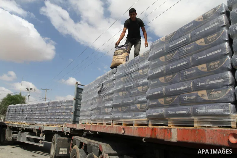 A Palestinian worker stands on a truck loaded with bags of cement after it entered the southern Gaza Strip from Israel through the Kerem Shalom crossing in Rafah on May 23, 2016. Israel said on May 22 it was lifting a ba...