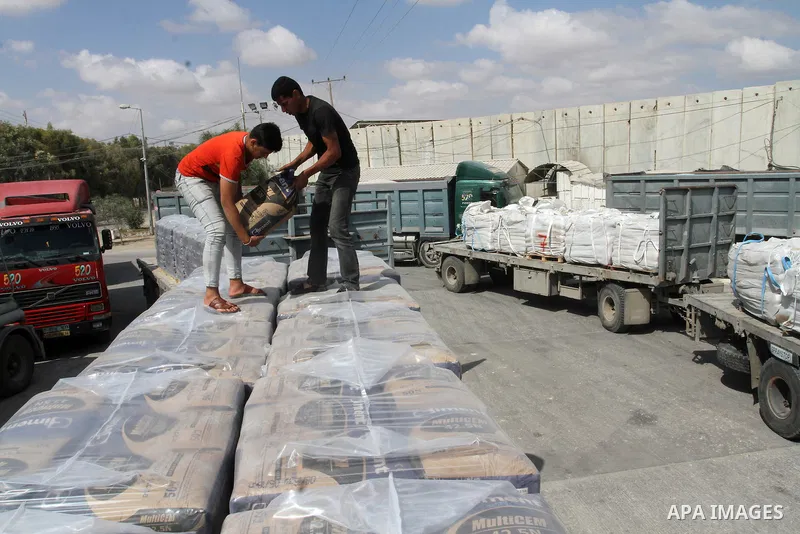 Palestinian workers stand on a truck loaded with bags of cement after it entered the southern Gaza Strip from Israel through the Kerem Shalom crossing in Rafah on May 23, 2016. Israel said on May 22 it was lifting a ban...