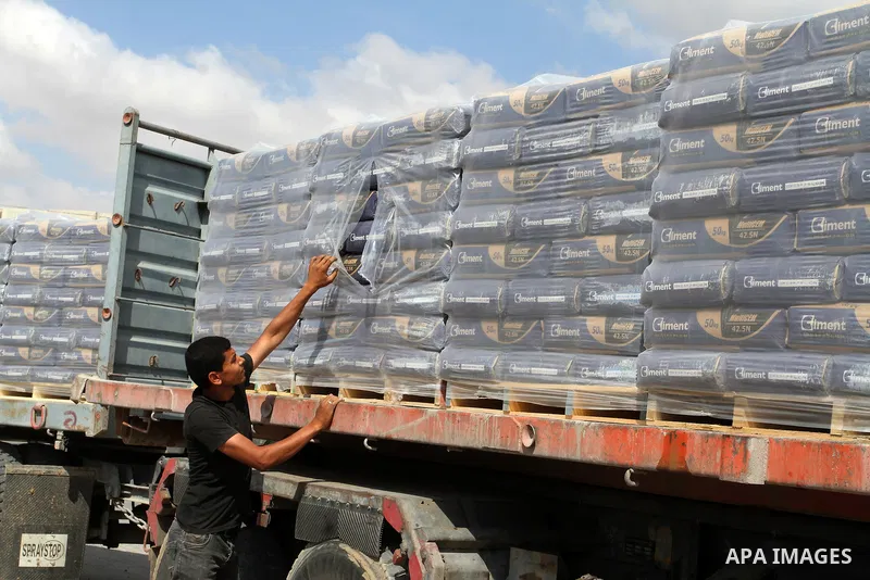 Palestinian workers stand on a truck loaded with bags of cement after it entered the southern Gaza Strip from Israel through the Kerem Shalom crossing in Rafah on May 23, 2016. Israel said on May 22 it was lifting a ban...