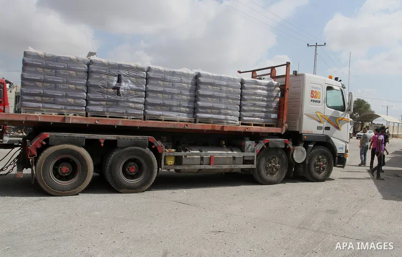 Palestinian workers stand on a truck loaded with bags of cement after it entered the southern Gaza Strip from Israel through the Kerem Shalom crossing in Rafah on May 23, 2016. Israel said on May 22 it was lifting a ban...