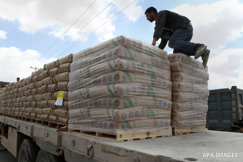 A Palestinian worker stands on a truck loaded with bags of cement after it entered the southern Gaza Strip from Israel through the Kerem Shalom crossing in Rafah on May 23, 2016. Israel said on May 22 it was lifting a ba...