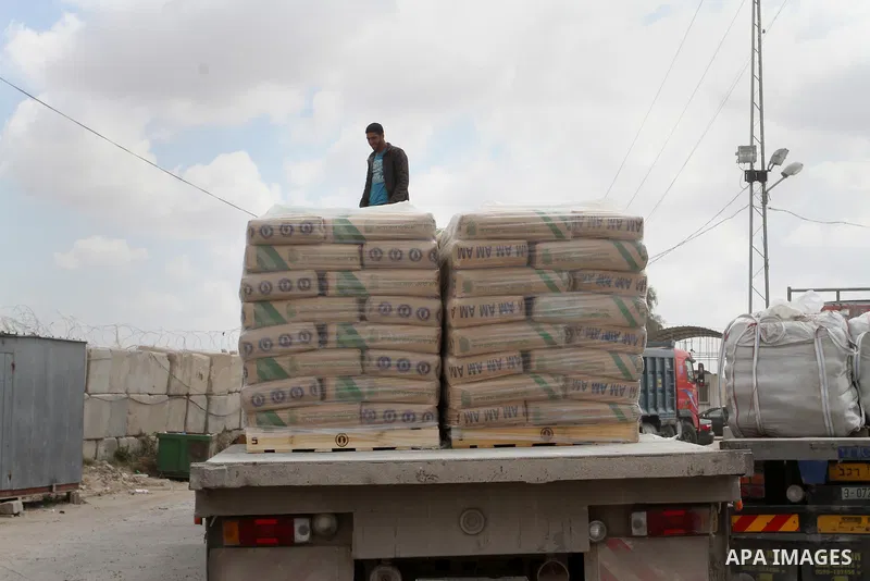 A Palestinian worker stands on a truck loaded with bags of cement after it entered the southern Gaza Strip from Israel through the Kerem Shalom crossing in Rafah on May 23, 2016. Israel said on May 22 it was lifting a ba...