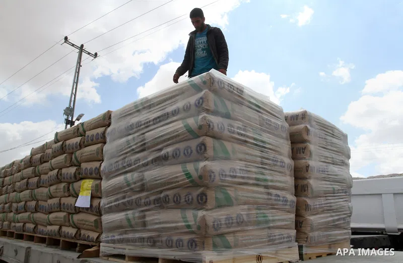 A Palestinian worker stands on a truck loaded with bags of cement after it entered the southern Gaza Strip from Israel through the Kerem Shalom crossing in Rafah on May 23, 2016. Israel said on May 22 it was lifting a ba...
