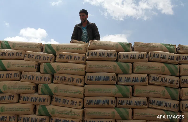 A Palestinian worker stands on a truck loaded with bags of cement after it entered the southern Gaza Strip from Israel through the Kerem Shalom crossing in Rafah on May 23, 2016. Israel said on May 22 it was lifting a ba...