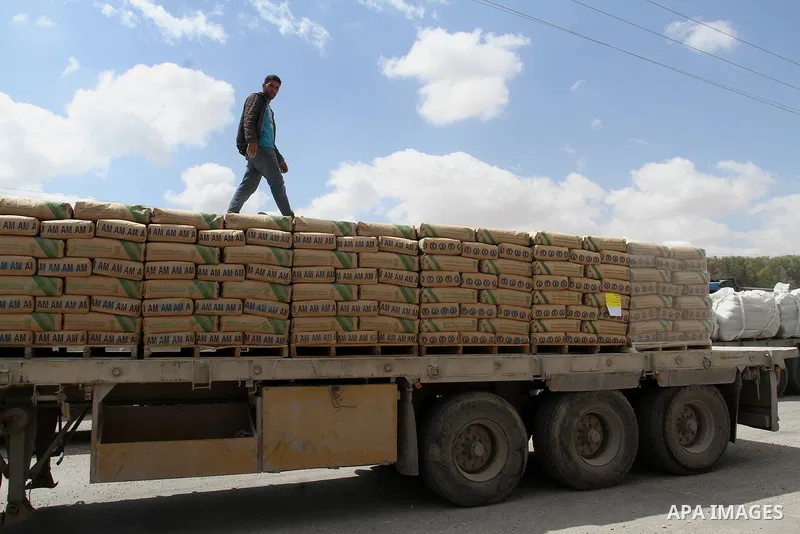 A Palestinian worker stands on a truck loaded with bags of cement after it entered the southern Gaza Strip from Israel through the Kerem Shalom crossing in Rafah on May 23, 2016. Israel said on May 22 it was lifting a ba...