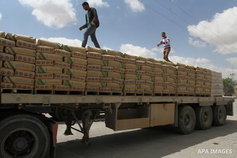 Palestinian workers stand on a truck loaded with bags of cement after it entered the southern Gaza Strip from Israel through the Kerem Shalom crossing in Rafah on May 23, 2016. Israel said on May 22 it was lifting a ban...