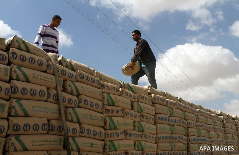 Palestinian workers stand on a truck loaded with bags of cement after it entered the southern Gaza Strip from Israel through the Kerem Shalom crossing in Rafah on May 23, 2016. Israel said on May 22 it was lifting a ban...
