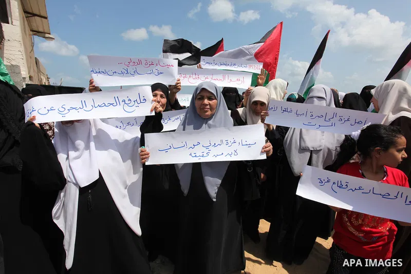 Palestinians hold placards during a protest against the Israeli blockade of the Gaza Strip at the Gaza seaport, on May 24, 2016. Photo by Ashraf Amra