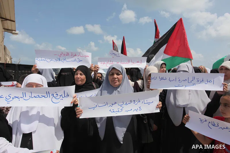 Palestinians hold placards during a protest against the Israeli blockade of the Gaza Strip at the Gaza seaport, on May 24, 2016. Photo by Ashraf Amra