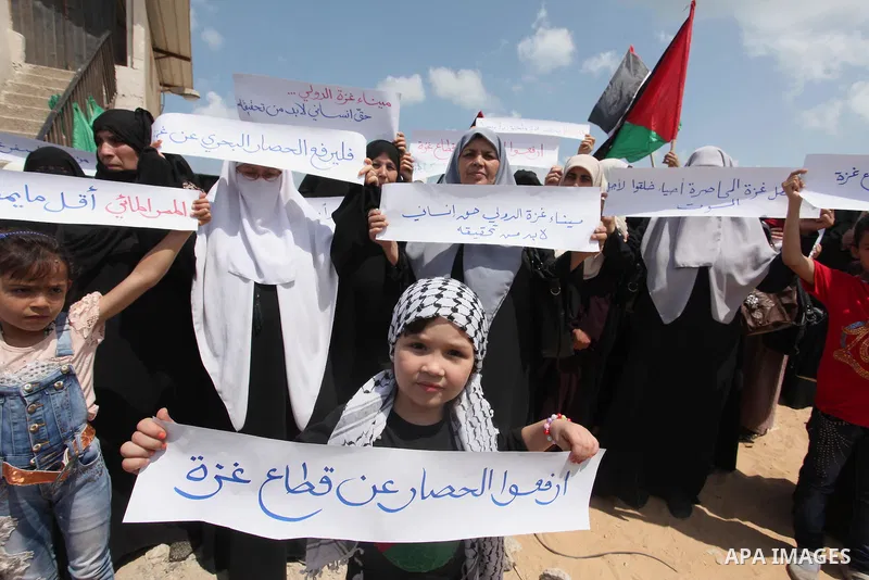 Palestinians hold placards during a protest against the Israeli blockade of the Gaza Strip at the Gaza seaport, on May 24, 2016. Photo by Ashraf Amra