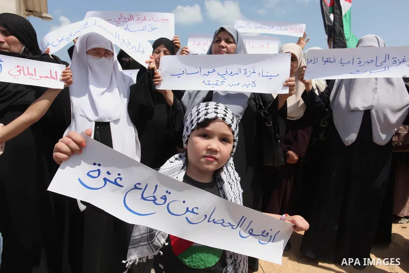 Palestinians hold placards during a protest against the Israeli blockade of the Gaza Strip at the Gaza seaport, on May 24, 2016. Photo by Ashraf Amra