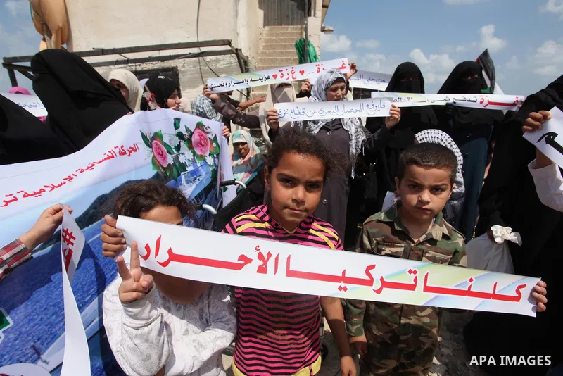 Palestinians hold placards during a protest against the Israeli blockade of the Gaza Strip at the Gaza seaport, on May 24, 2016. Photo by Ashraf Amra