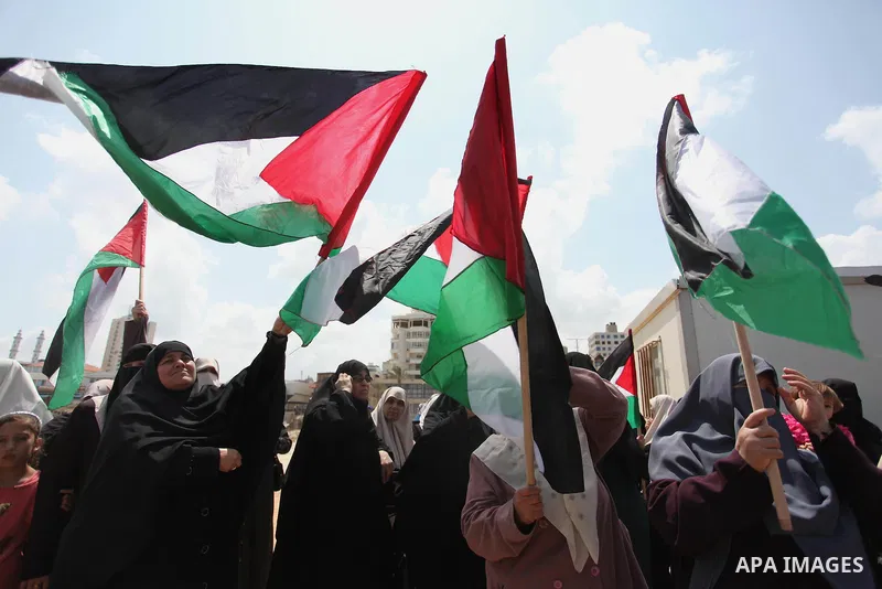 Palestinians hold placards during a protest against the Israeli blockade of the Gaza Strip at the Gaza seaport, on May 24, 2016. Photo by Ashraf Amra