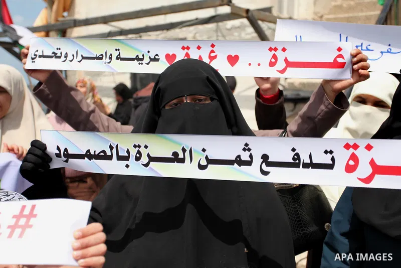 Palestinians hold placards during a protest against the Israeli blockade of the Gaza Strip at the Gaza seaport, on May 24, 2016. Photo by Ashraf Amra
