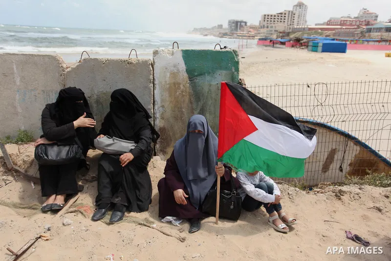 Palestinians hold placards during a protest against the Israeli blockade of the Gaza Strip at the Gaza seaport, on May 24, 2016. Photo by Ashraf Amra