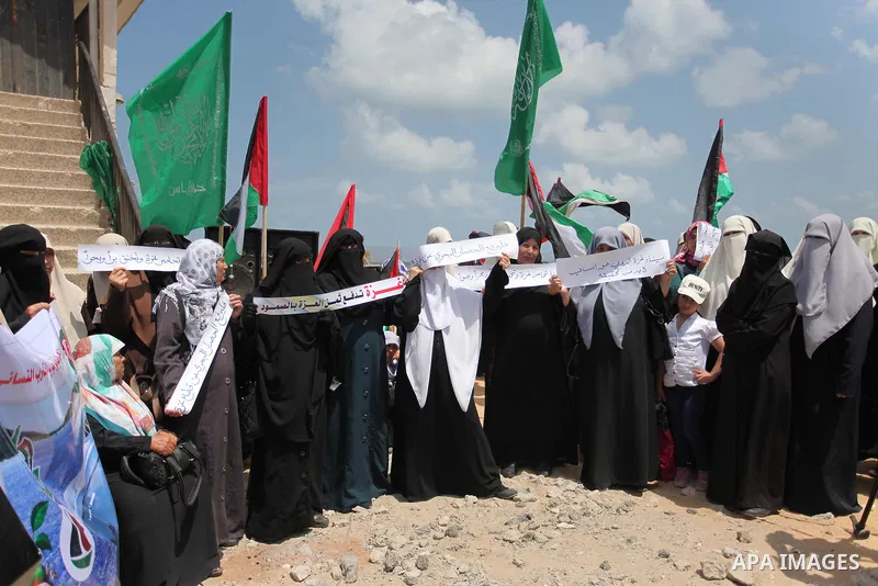 Palestinians hold placards during a protest against the Israeli blockade of the Gaza Strip at the Gaza seaport, on May 24, 2016. Photo by Ashraf Amra