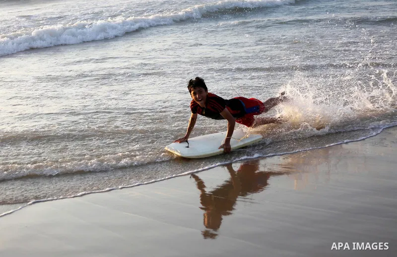 Palestinian youths enjoy a day at the beach of the Mediterranean sea on the coast of Gaza city during sunset, on May 24, 2016. Photo by Mohammed Asad