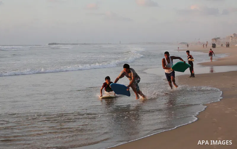 Palestinian youths enjoy a day at the beach of the Mediterranean sea on the coast of Gaza city during sunset, on May 24, 2016. Photo by Mohammed Asad