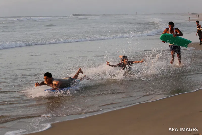 Palestinian youths enjoy a day at the beach of the Mediterranean sea on the coast of Gaza city during sunset, on May 24, 2016. Photo by Mohammed Asad
