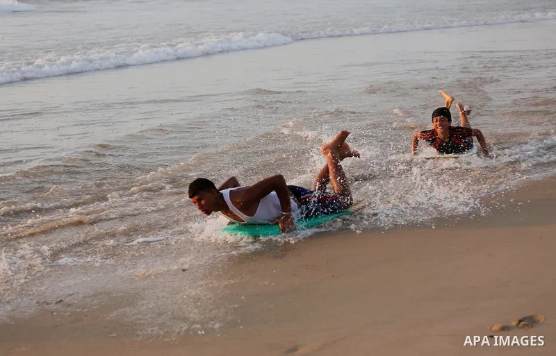 Palestinian youths enjoy a day at the beach of the Mediterranean sea on the coast of Gaza city during sunset, on May 24, 2016. Photo by Mohammed Asad