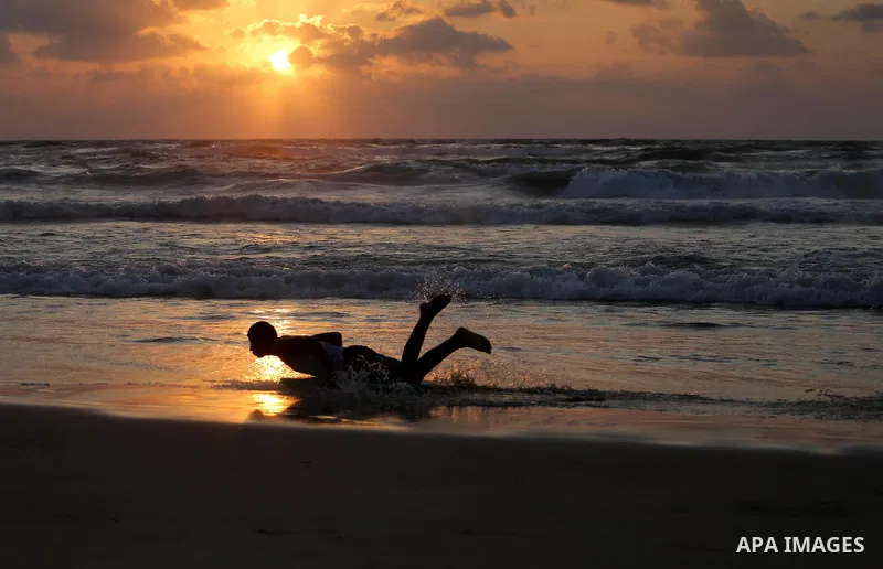 Palestinian youths enjoy a day at the beach of the Mediterranean sea on the coast of Gaza city during sunset, on May 24, 2016. Photo by Mohammed Asad